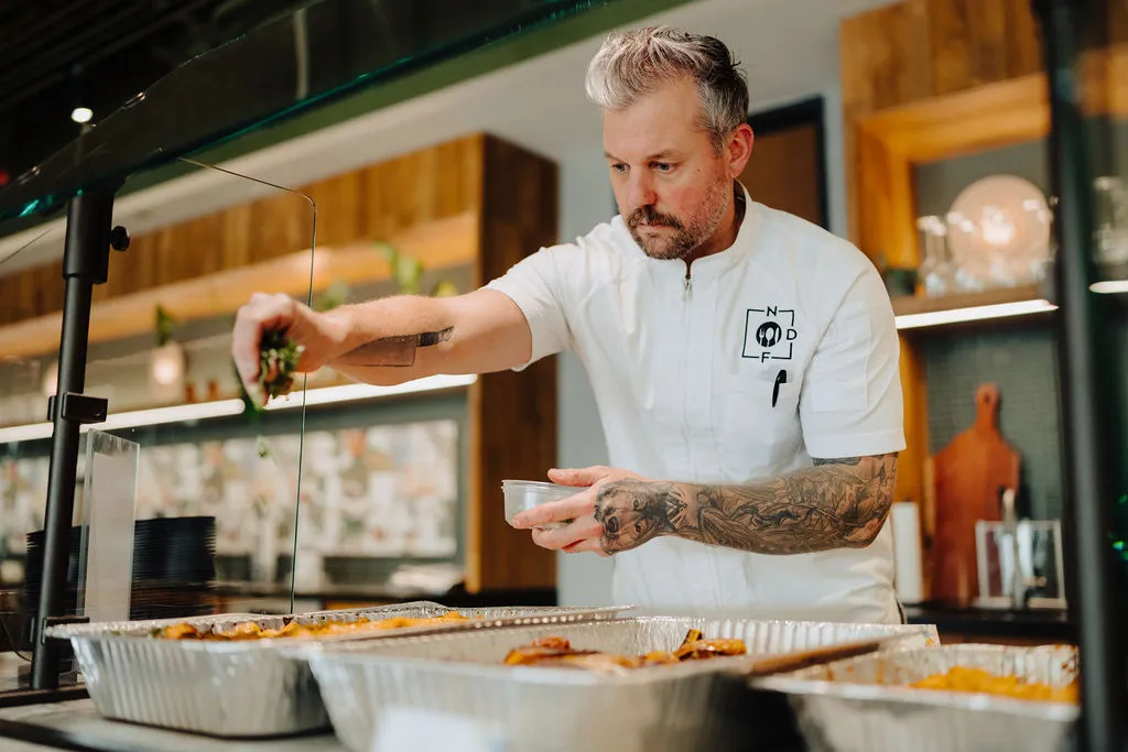 An NDF chef finishing a dish in the kitchen