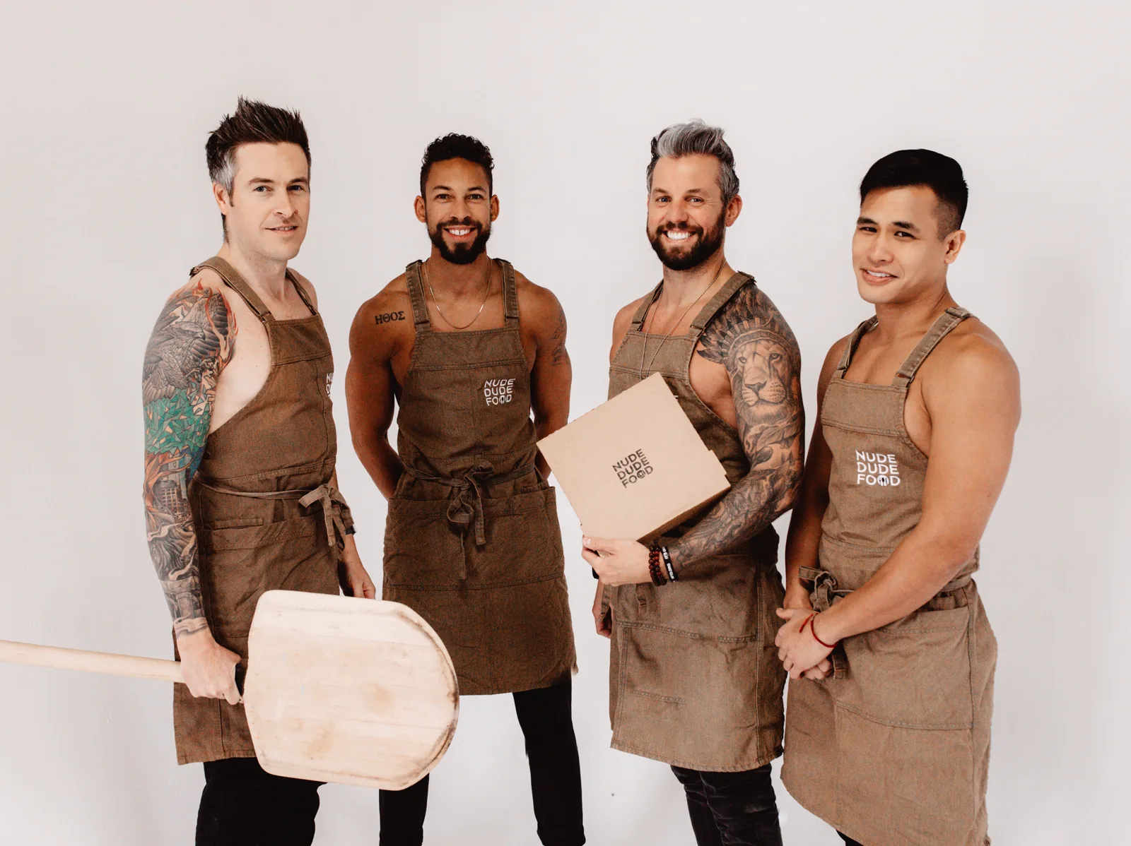 Four Nude Dude Food team members standing together in aprons